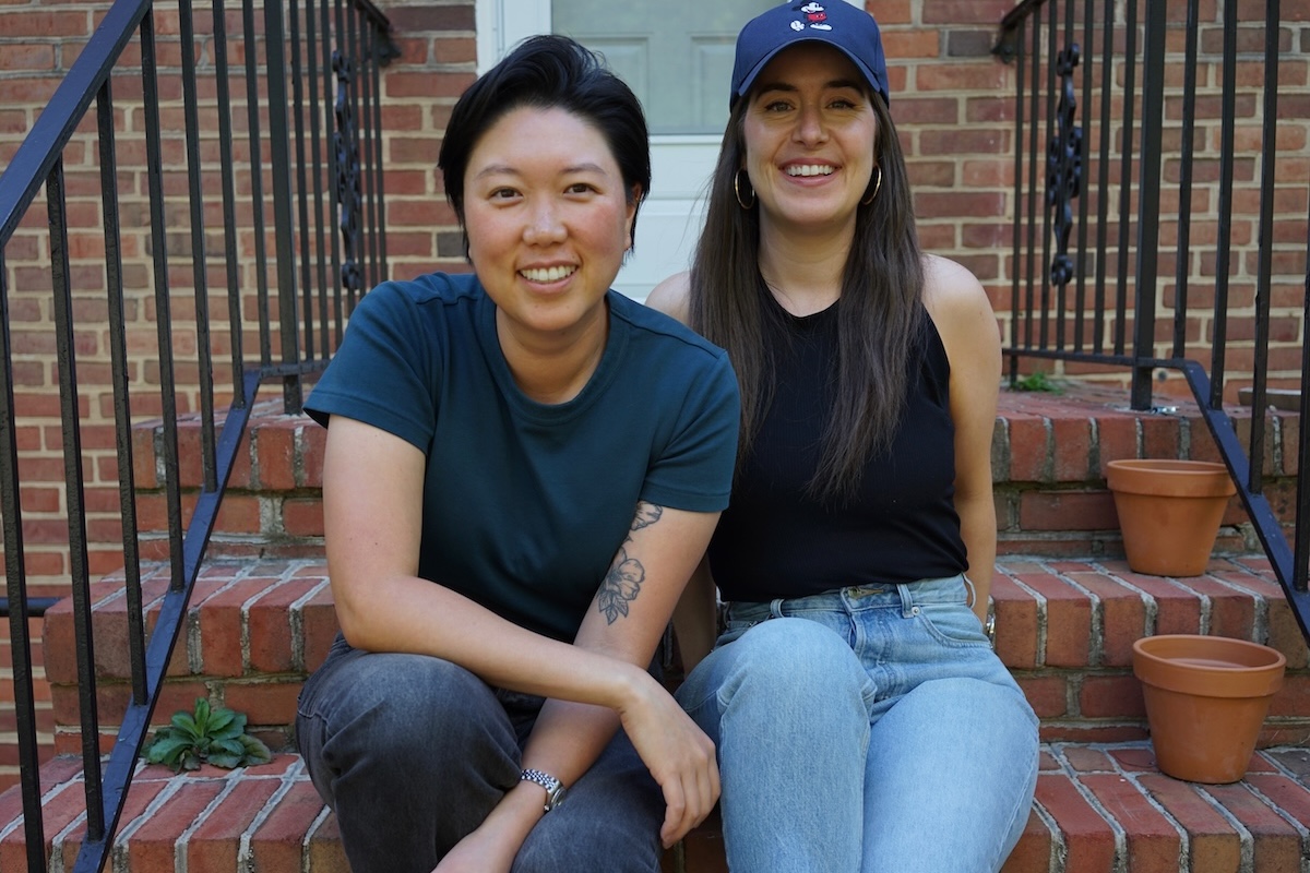 This photo shows Emily Kwak and Christina Cord sitting side by side on the stoop of a house.