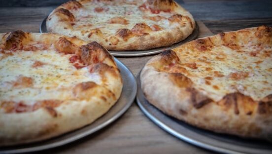 This photo shows three whole cheese pizzas.