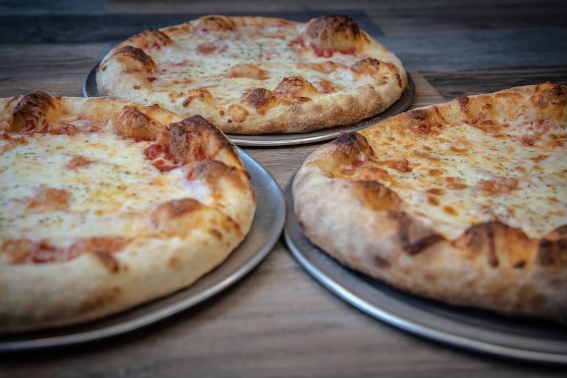 This photo shows three whole cheese pizzas.