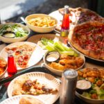 This photo shows a wide array of menu items at Barclay Pies, including pizzas, wings, salads and fries, plus various beverages.