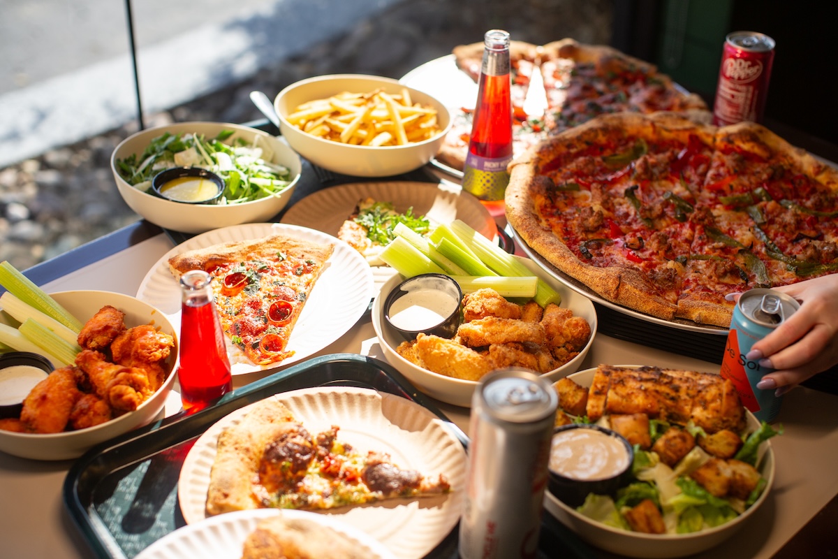 This photo shows a wide array of menu items at Barclay Pies, including pizzas, wings, salads and fries, plus various beverages.