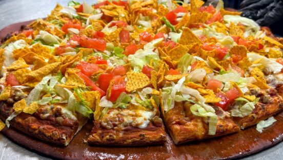 This photo shows Happy Joe's taco pizza topped with cheese, ground beef, lettuce, tomatoes and corn chips.