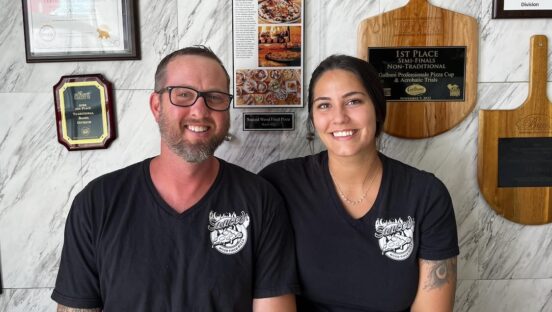 This photo shows Craig and Desirae sitting together in an area of their restaurant.