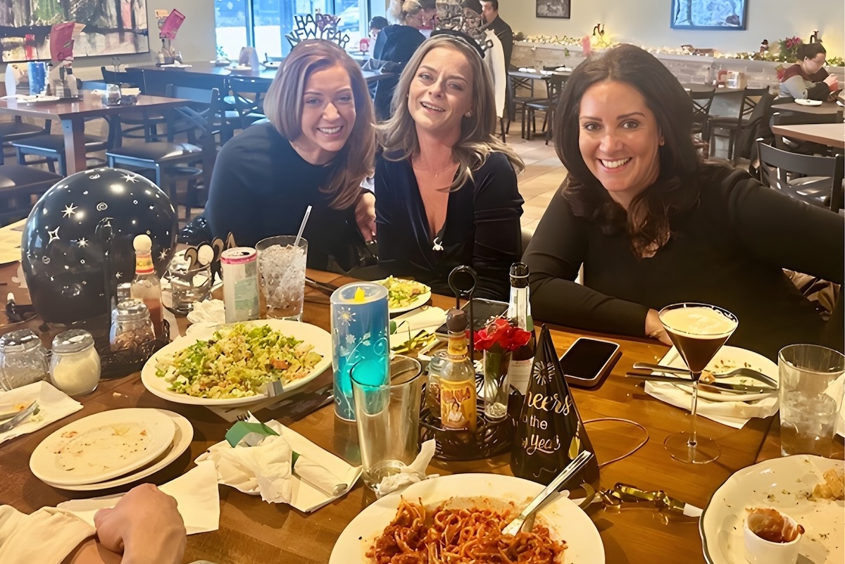 This photo shows three happy women, all wearing black, sitting at a table with drinks and empty plates after a meal at Leona's.