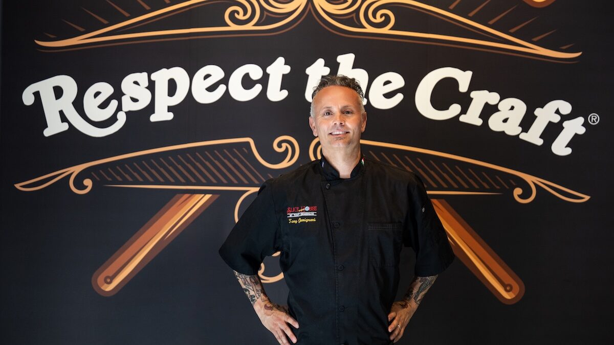 This photo shows Tony Gemignani, hands on hips, standing front of a giant mural with the words "Respect the Craft"