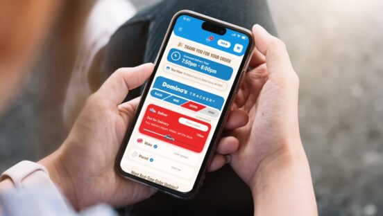 This photo shows someone holding a smartphone and looking at the Domino's pizza tracker after placing an order.