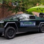 This photo shows a Cyber Pizza Truck parked in front of a large house with a yellow umbrella behind it.