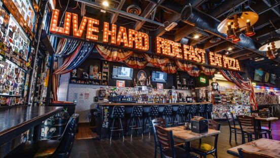 This photo shows the interior of Evel Pie. Above the bar are the words: Live Hard. Ride Fast. Eat Pizza.