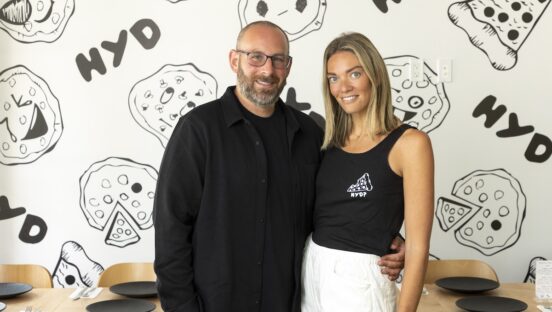 This photo shows Garett and Gabby Goodman standing next to each other in their pizzeria.