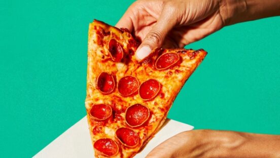 This photo shows a person's hands holding a slice of pepperoni pizza.
