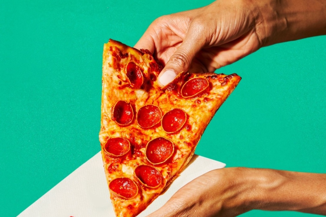 This photo shows a person's hands holding a slice of pepperoni pizza.