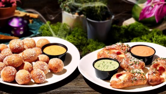 This photo shows Mellow Mushroom's Mellow Rollz and Pretzel Bites in separate plates along with cups of dipping sauce.