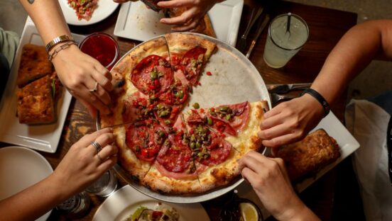 This photo shows customers sharing a pizza from Pizza Domenica in New Orleans.