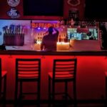 This photo shows the interior of Raffaeles Pizza, darkly lit, with a shadowy man standing behind the bar with his back to the camera.