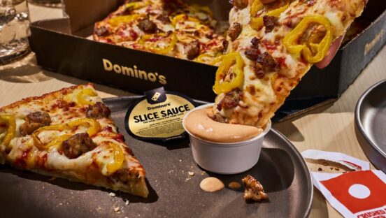 This photo shows a tasty-looking pizza slice being dipped into a little cup of the Slice Sauce.
