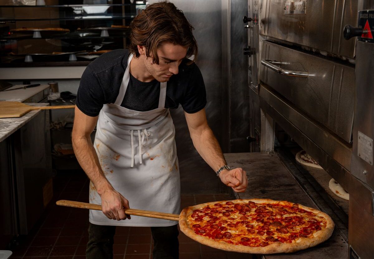 Mason Lesser, founder of Marina’s in Philadelphia, removes a pizza from the oven.
