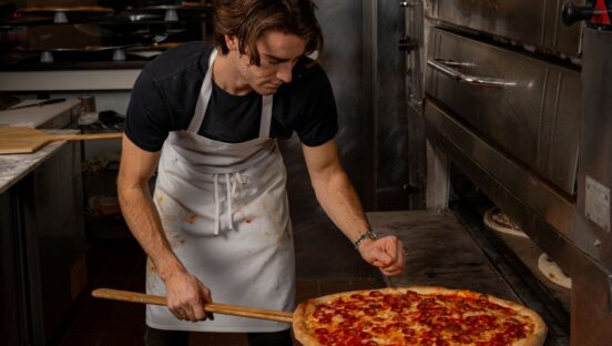 Mason Lesser, founder of Marina’s in Philadelphia, removes a pizza from the oven.