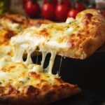 This photo shows a slice of pizza being extracted from a whole pizza topped with four different cheeses.