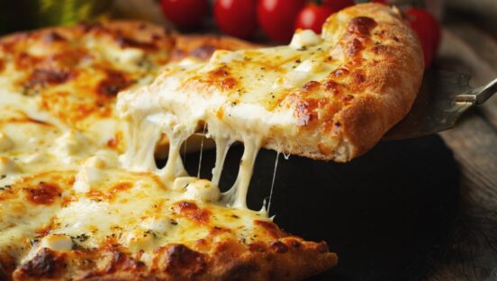 This photo shows a slice of pizza being extracted from a whole pizza topped with four different cheeses.