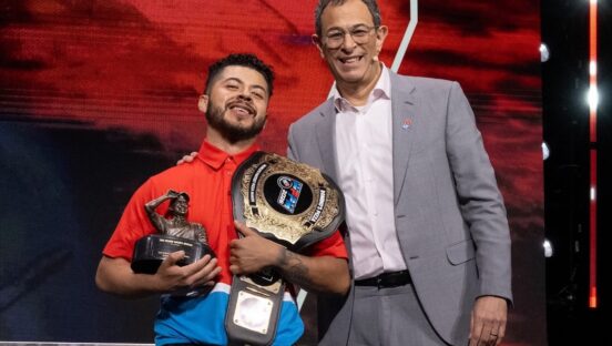 This photo shows Richard Delcid holding his trophy and championship belt while standing next to the Domino's Pizza CEO.