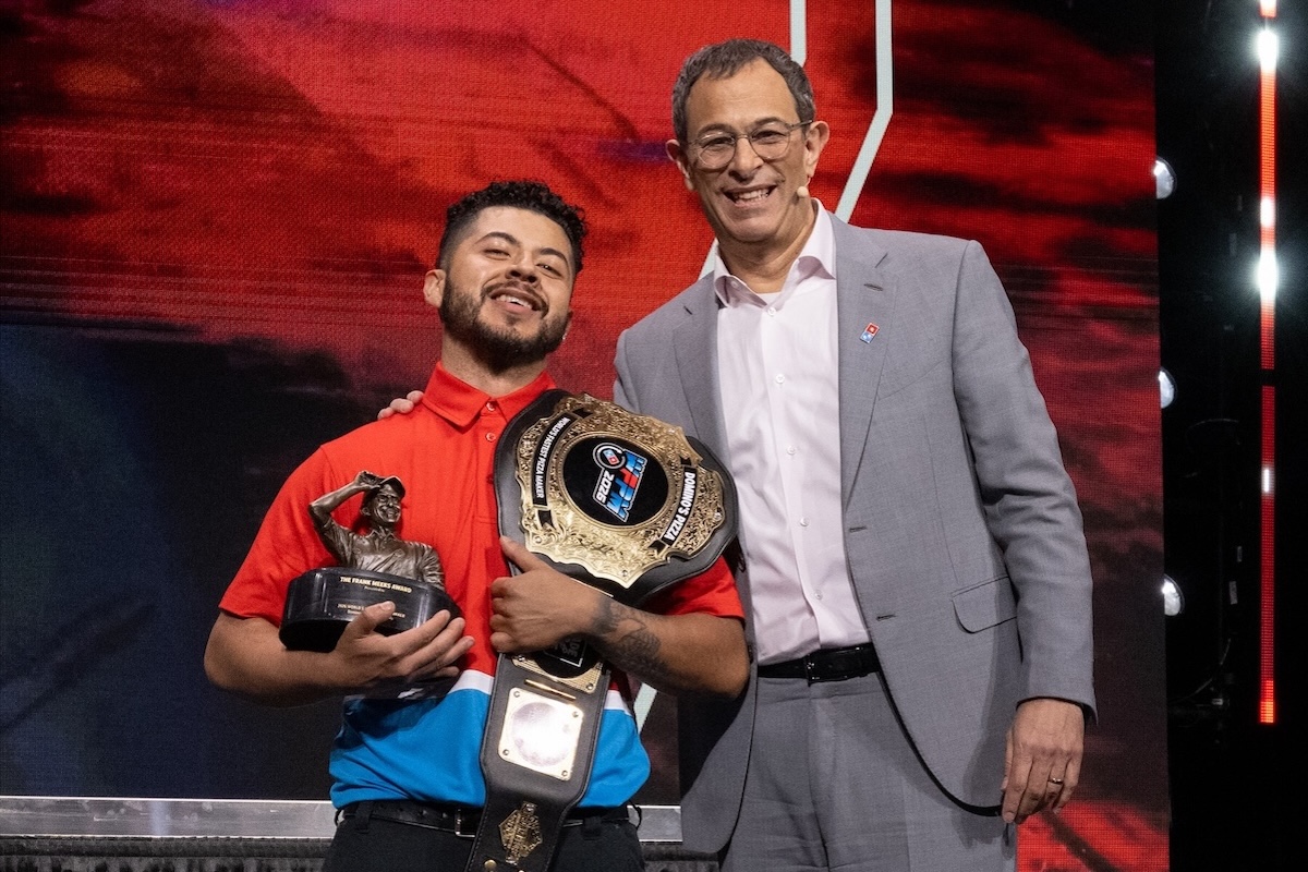 This photo shows Richard Delcid holding his trophy and championship belt while standing next to the Domino's Pizza CEO.