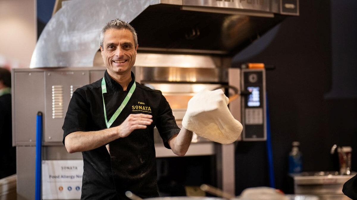 Fabio Errante, a pizzaiolo, stretches dough in a pizzeria kitchen.