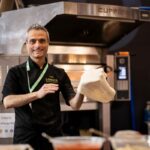 Fabio Errante, a pizzaiolo, stretches dough in a pizzeria kitchen.