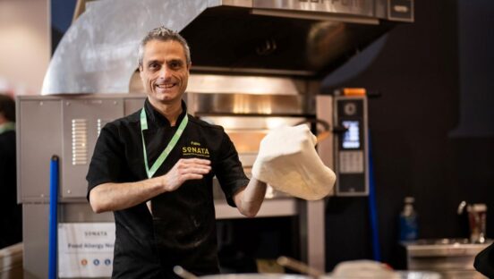 Fabio Errante, a pizzaiolo, stretches dough in a pizzeria kitchen.