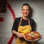 Pizzaiola Giorgia Caporuscio holds a pizza