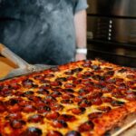 This photo shows a delicious looking rectangular pizza topped with pepperoni.