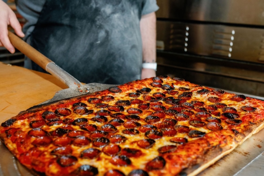 This photo shows a delicious looking rectangular pizza topped with pepperoni.