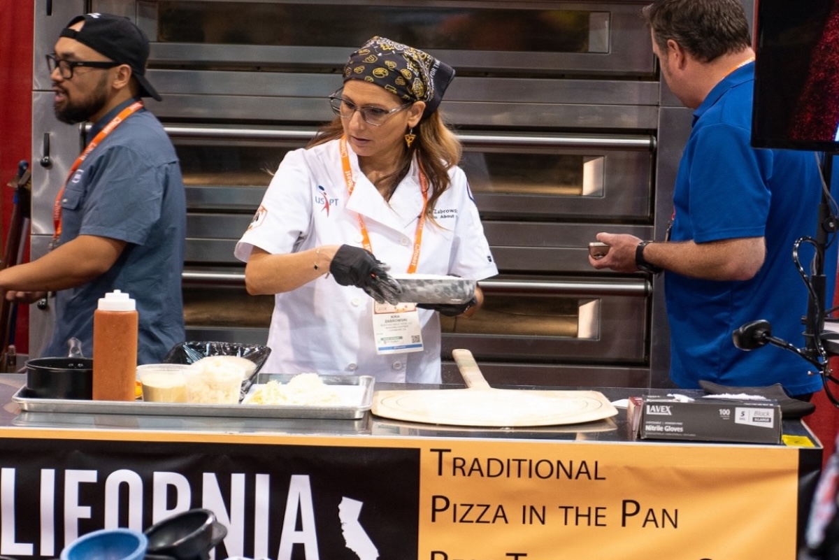 This photo shows Kira Zabrowski in a white U.S. Pizza Team chef coat working on a recipe at the California Pizza Challenge.