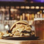 This photo shows Old Chicago's Stacked & Smashed burger with a glass of beer.