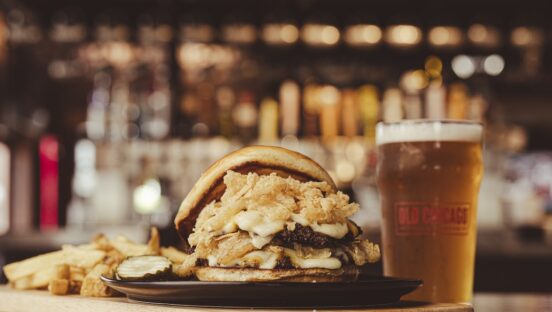 This photo shows Old Chicago's Stacked & Smashed burger with a glass of beer.