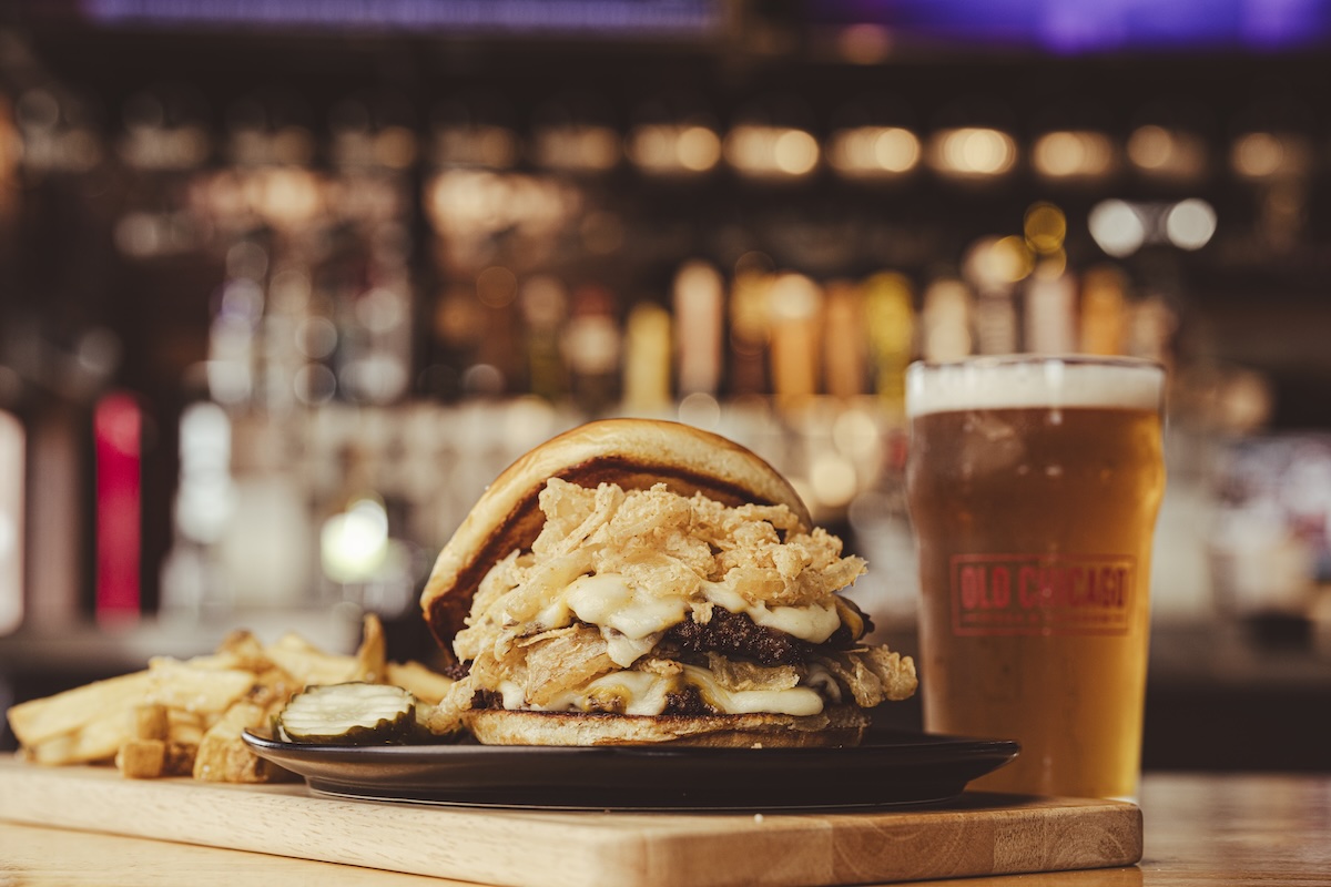 This photo shows Old Chicago's Stacked & Smashed burger with a glass of beer.
