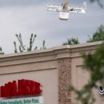 This photo shows a delivery drone hovering over a Papa Johns store.