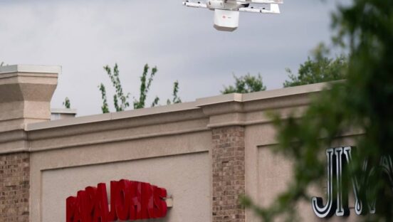 This photo shows a delivery drone hovering over a Papa Johns store.