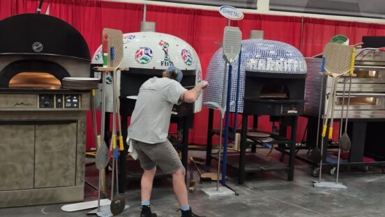 This photo shows Silvio peeling his pizza into a dome-shaped oven at Pizza Expo.