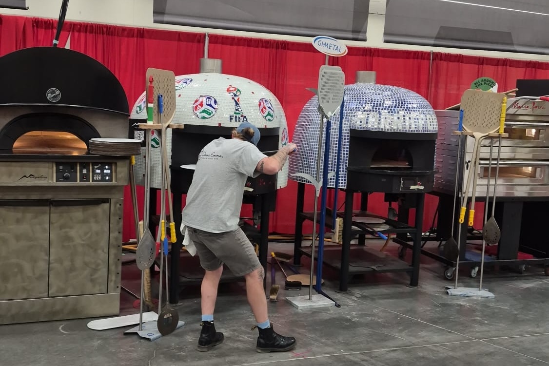 This photo shows Silvio peeling his pizza into a dome-shaped oven at Pizza Expo.