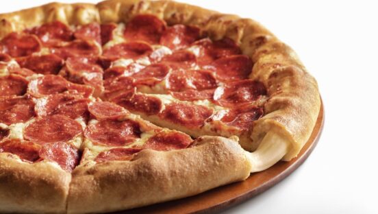 This photo shows a whole stuffed crust pizza from Pizza Hut, with cheese oozing out from a slice in the foreground.