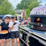 Emily Kwak and Christina Cord, owners and operators of Pizzeria Coco, work at their mobile pizza oven.