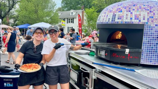 Emily Kwak and Christina Cord, owners and operators of Pizzeria Coco, work at their mobile pizza oven.