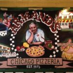 This photo shows a mural on the wall of Armand's featuring its founder with a pizza.