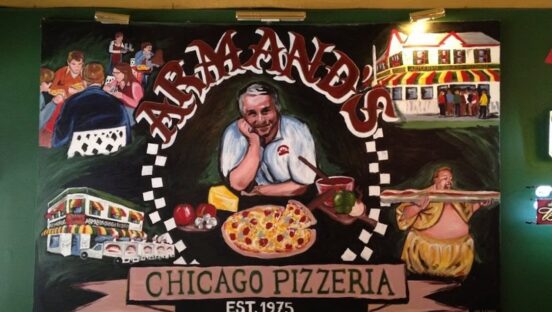This photo shows a mural on the wall of Armand's featuring its founder with a pizza.
