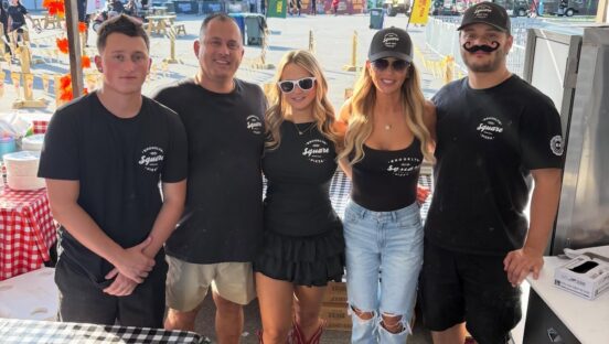 This photo shows the owner of Brooklyn Square Pizza lined up with two young men and two young women all wearing black t-shirts with the brand's logo.