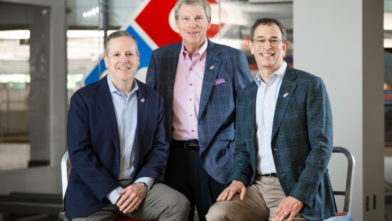This photo shows Joe Jordan, David Brandon and Russell Weiner side by side, with Brandon standing in the middle and Jordan and Weiner seated on either side of him.