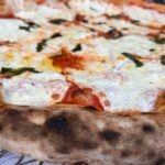 This photo shows a close-up of a Margherita pizza with nicely charred crust edges.