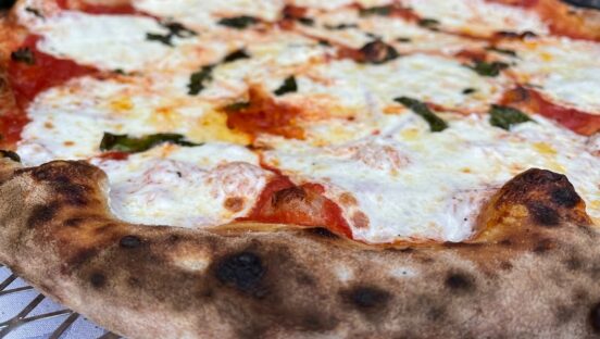 This photo shows a close-up of a Margherita pizza with nicely charred crust edges.