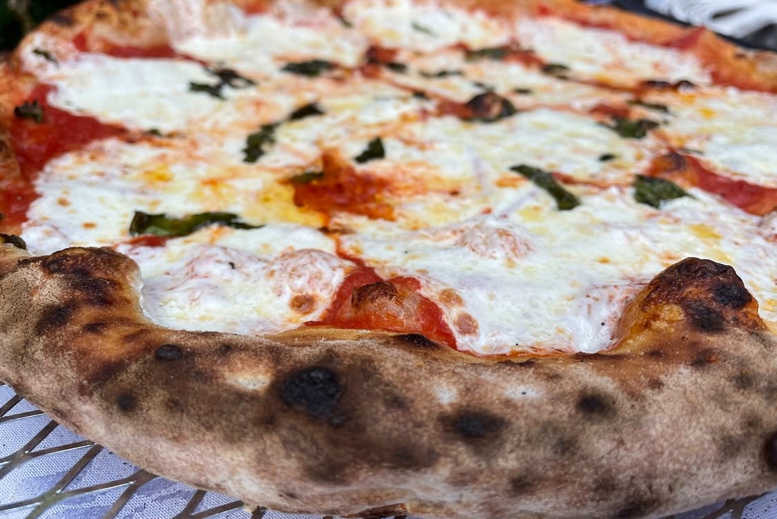 This photo shows a close-up of a Margherita pizza with nicely charred crust edges.