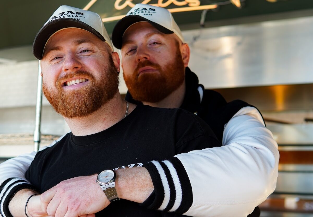 This photo shows the two brothers together. Chadd is standing behind Brett and has his arms wrapped affectionately around Brett's shoulders. Both men are smiling.